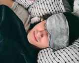 A man sleeping under the Weighted Sleep Mask. 